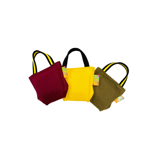 Three soft bite pillows with handles, in red, yellow, and green colors, designed for training dogs.